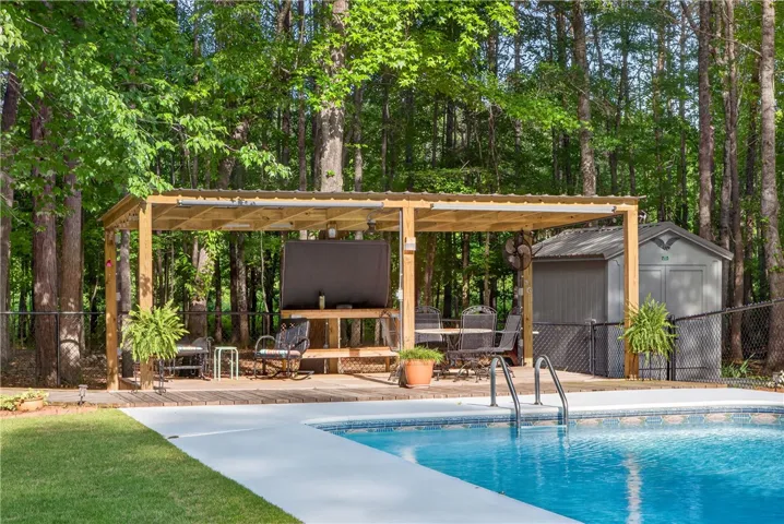 A private backyard oasis features a shimmering pool alongside a wooden deck and a charming gazebo, perfect for outdoor relaxation.