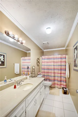 A well-appointed bathroom features a large vanity with ample storage and a cheerful striped shower curtain.