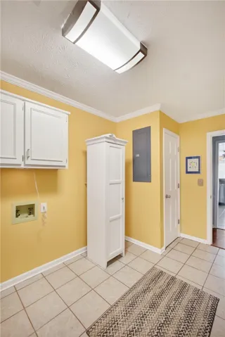 Functional laundry space featuring durable tile flooring and convenient upper cabinetry.