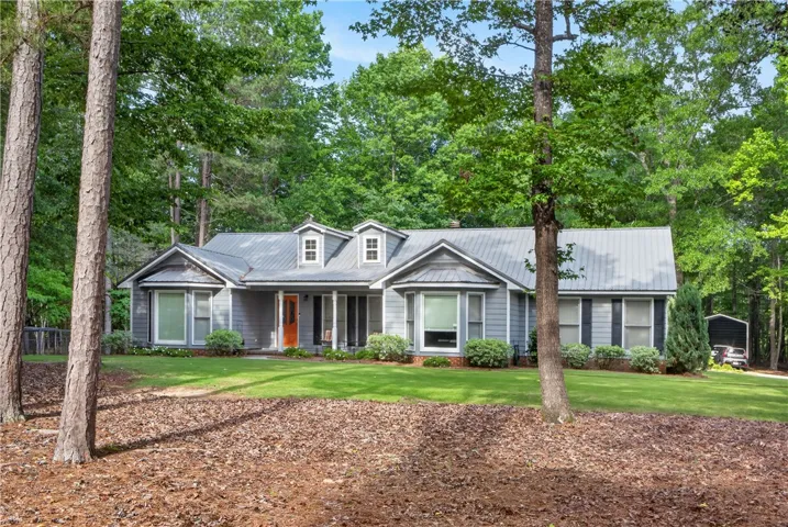 A classic ranch home nestled among mature trees with a neat, verdant lawn.