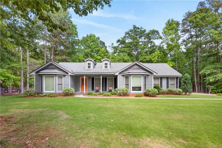 A well-maintained ranch-style home, framed by mature trees, features a welcoming front porch and manicured lawn.