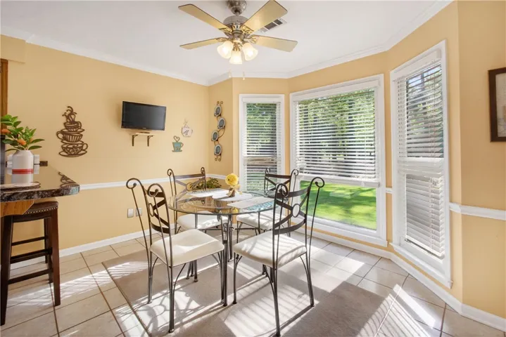 A well-lit breakfast area offers panoramic backyard views through large bay windows, perfect for morning meals.