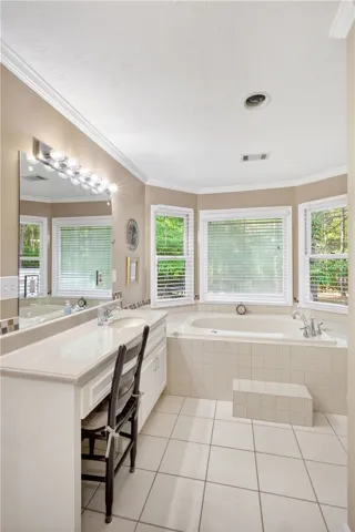 A deep soaking tub awaits in this sun-drenched primary bathroom featuring a convenient vanity and ample counter space.