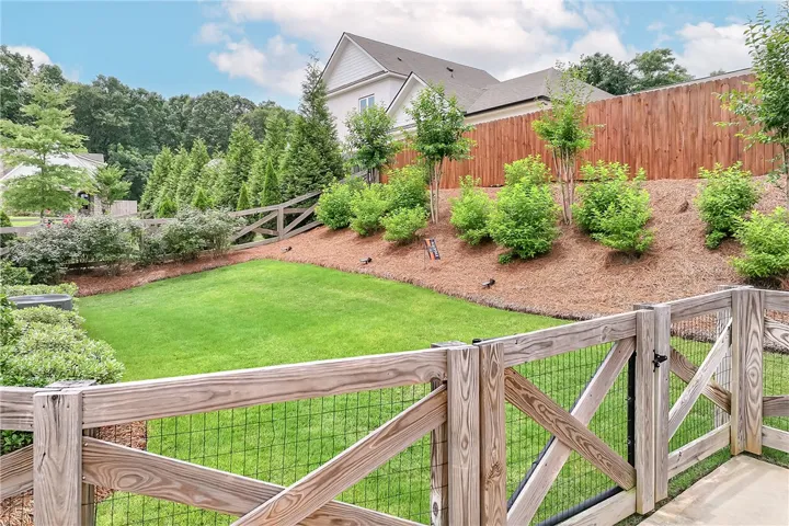 A tiered backyard features a vibrant green lawn and a natural wood fence, offering a private outdoor retreat.