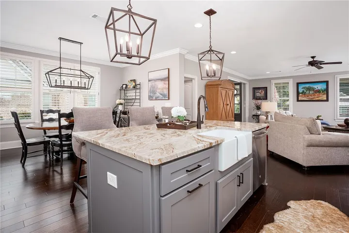 A central kitchen island featuring a farmhouse sink provides practical workspace and informal seating for meals.