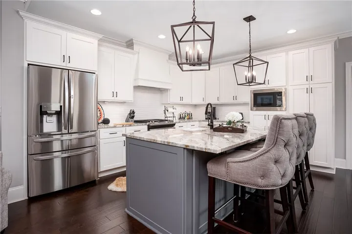 White cabinetry and dark flooring highlight this chef's kitchen, centered by a large island.