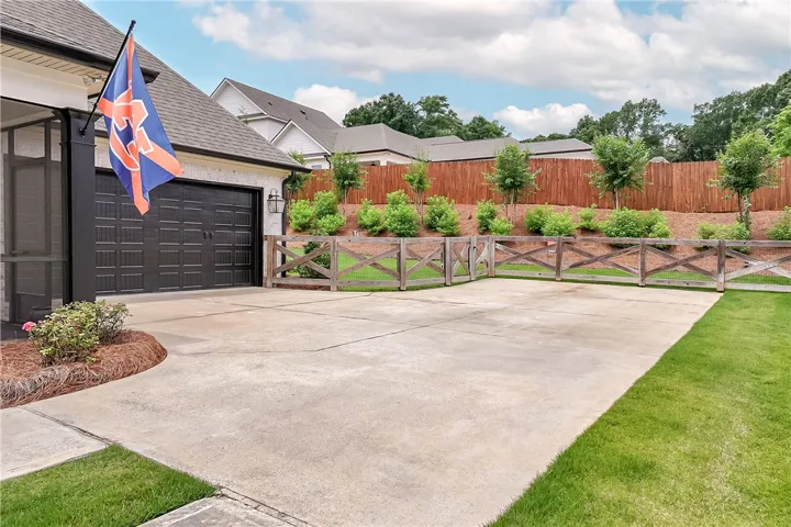 Concrete driveway and lush lawn define this inviting exterior with a charming wooden fence.