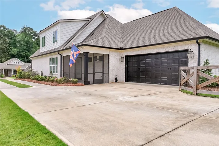 A classic brick exterior and black garage doors define this welcoming home, with a spacious driveway providing ample parking.