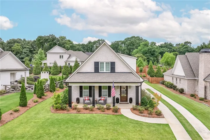 An inviting front porch welcomes guests to this classic brick residence, complete with a long, elegant driveway.