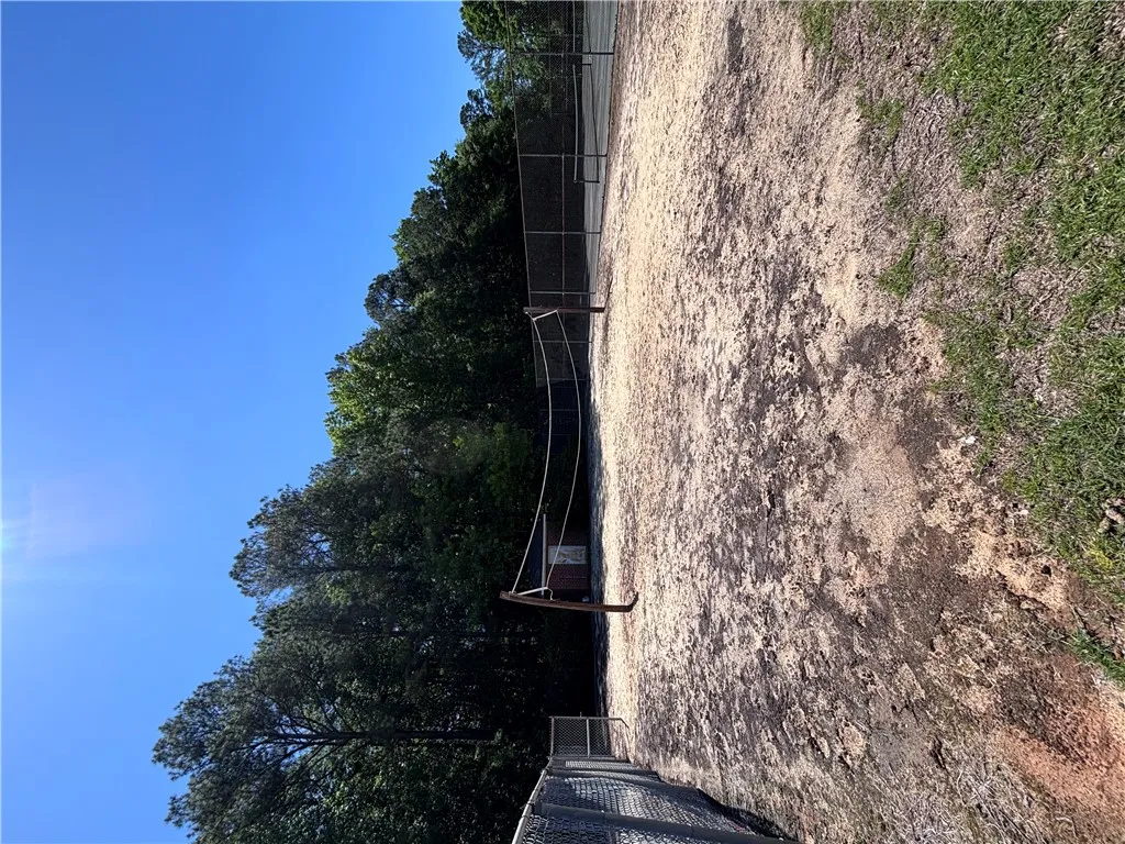 A well-maintained tennis court awaits, surrounded by mature trees for a tranquil playing environment.