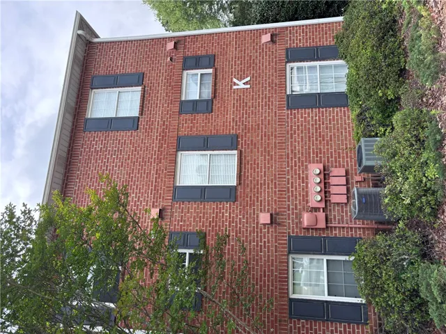 A classic brick exterior, framed by vibrant greenery, offers enduring curb appeal.