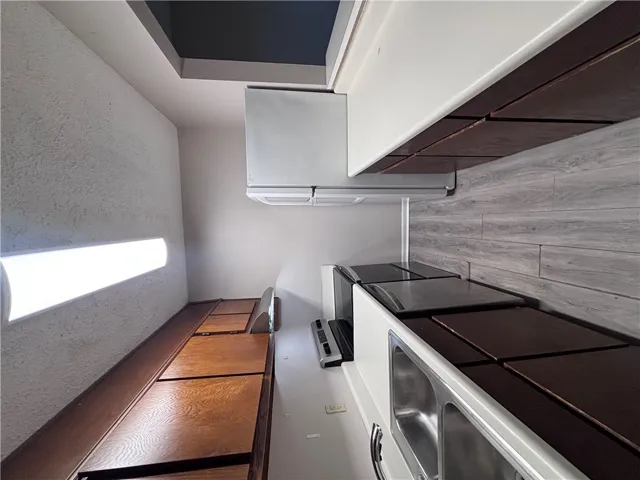 A compact kitchen boasts wood cabinetry, white countertops, and contemporary appliances for efficient meal preparation.
