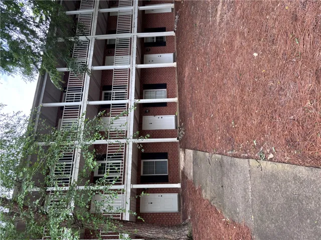 Multi-level brick facade with multiple units, each featuring an individual entry.