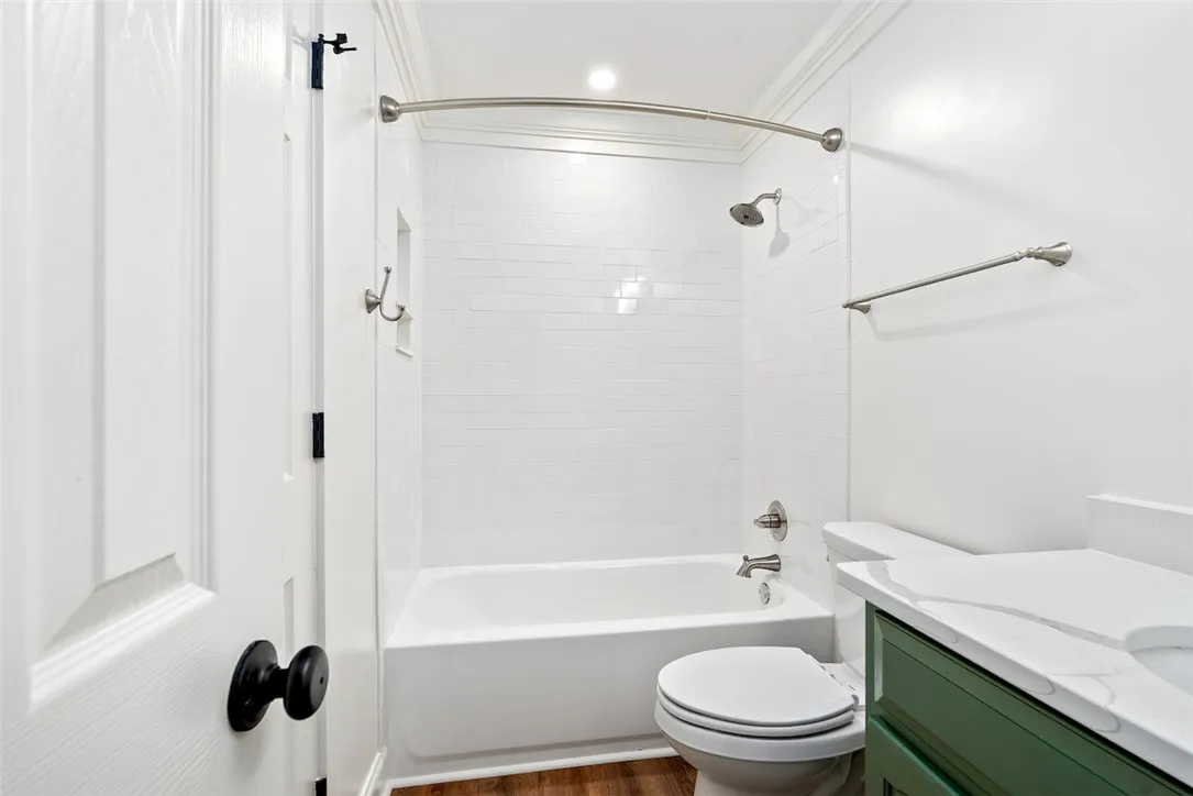 A refreshing bathroom showcases a crisp white subway tile shower and a striking green vanity with white countertops.