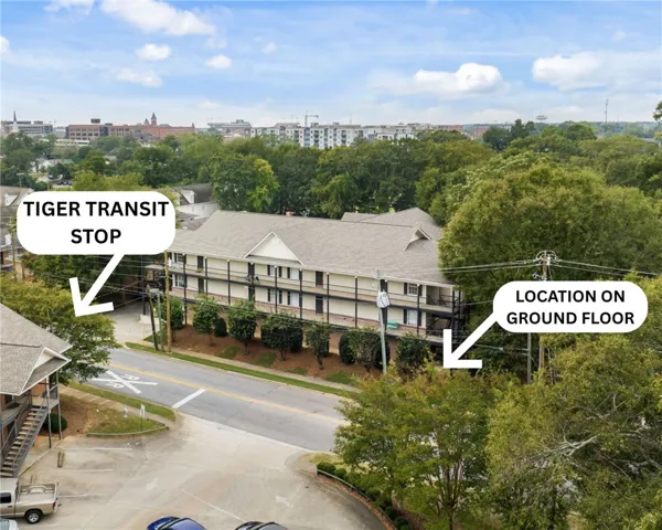 An aerial perspective reveals a multi-level residential building nestled amongst abundant mature trees and adjacent to a thoroughfare.