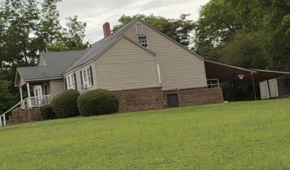 A classic facade featuring brick and siding, complemented by a covered side entrance.