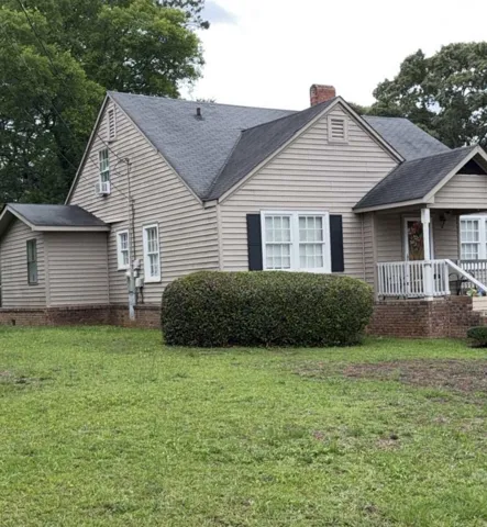 A classic exterior with wood siding, a welcoming porch, and a lush green lawn.