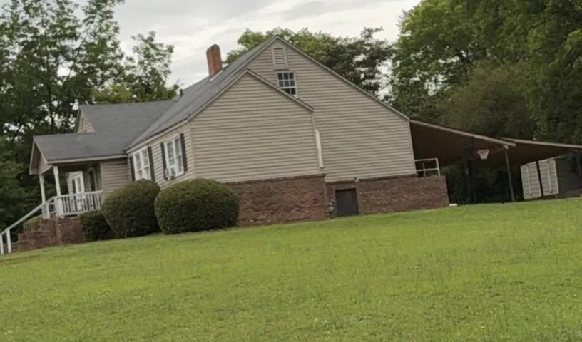A classic facade featuring brick and siding, complemented by a covered side entrance.
