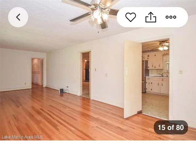 Warm hardwood floors and a ceiling fan enhance this inviting interior space.