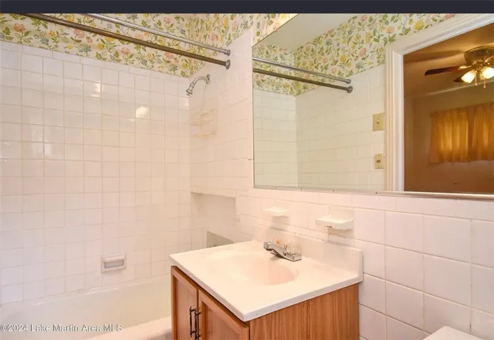 A well-maintained bathroom with a white tiled shower and a light wood vanity.