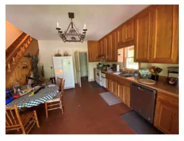 A functional kitchen with wood cabinetry and essential appliances offers a cozy dining space.