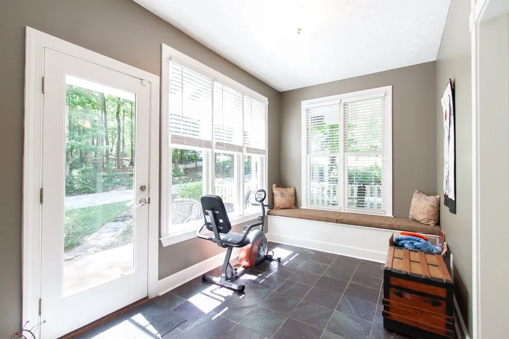 Sun-filled room with large windows and a built-in window seat, offering a serene view of the surrounding trees.