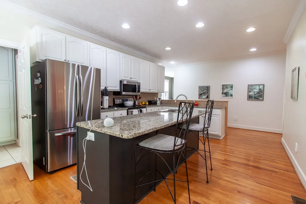 A chef's kitchen features rich wood flooring, granite counters, and stainless appliances for culinary perfection.
