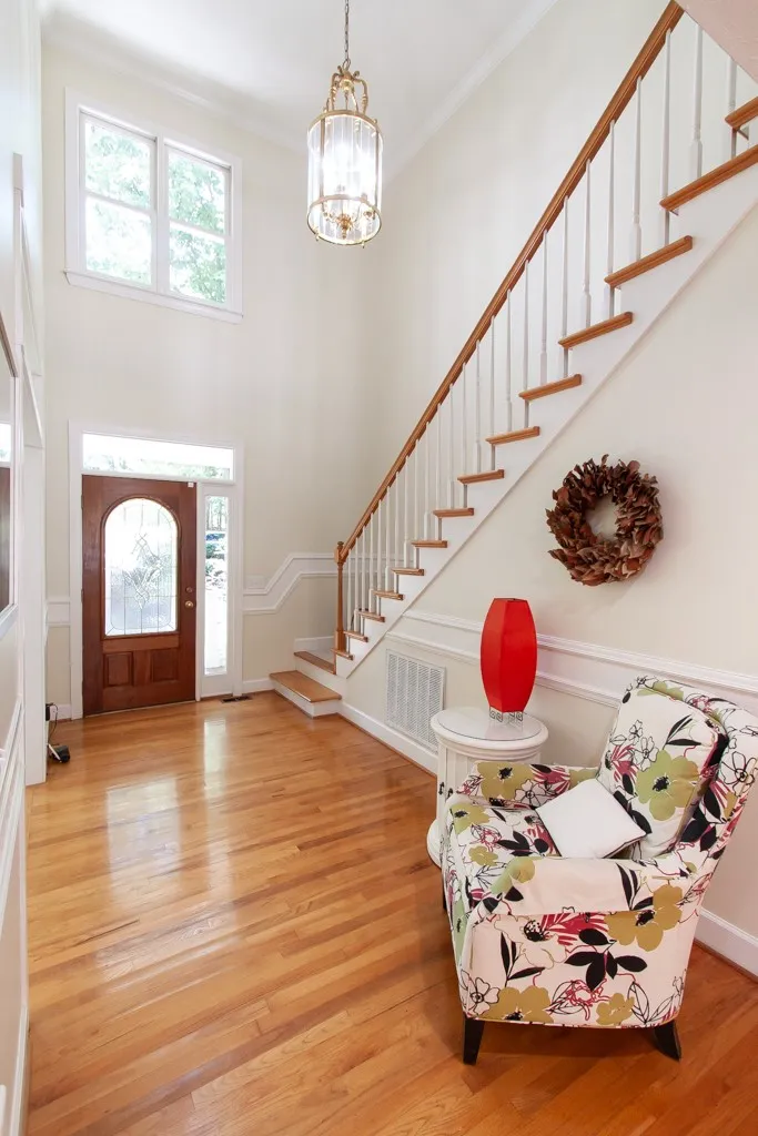 A graceful staircase ascends from a welcoming foyer featuring a polished hardwood floor and a sun-filled transom window.