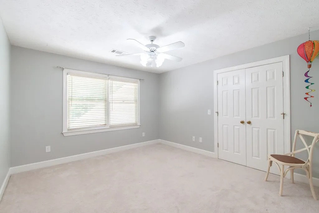 Bedroom 3 without furniture. A well-lit bedroom features plush carpeting and a convenient ceiling fan for comfort.