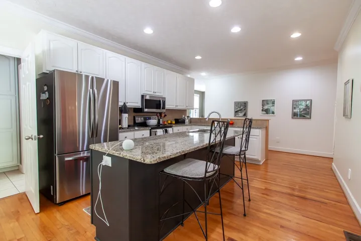 A chef's kitchen features rich wood flooring, granite counters, and stainless appliances for culinary perfection.