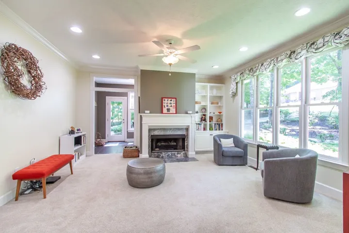 A well-lit living area features a stately fireplace, built-in shelving, and broad windows.