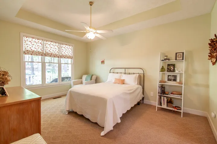 Located on the first floor. Natural light floods this inviting bedroom, featuring a tray ceiling and practical carpeted flooring.