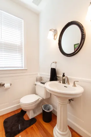 Hardwood floors and wainscoting create a timeless, refined bathroom ambiance.