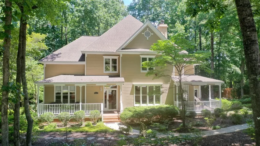 Nestled amidst lush greenery, this residence presents a welcoming facade with a covered front porch and expansive side porch.