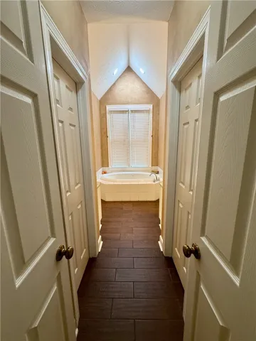 Enter a primary bathroom oasis featuring a deep soaking tub and textured flooring.
