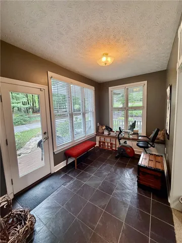 located off the side entry porch, this versatile bonus room features wide windows, providing abundant natural light and slate tile flooring.