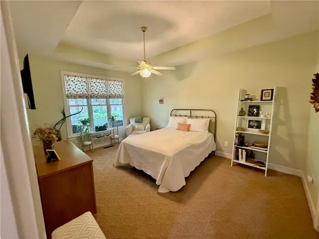 A tranquil sanctuary, this primary bedroom features vaulted ceilings and large windows overlooking lush greenery.