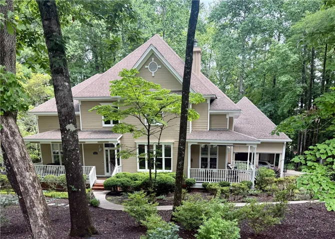 A welcoming front porch extends across this private residence, nestled amongst abundant greenery.