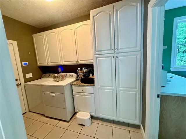 Ample cabinetry provides essential storage in this well-appointed laundry area. Pantry cabinet features pull out drawers for easy access to items.