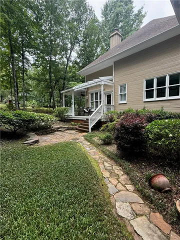 A flagstone path winds through verdant landscaping towards a charming covered porch.