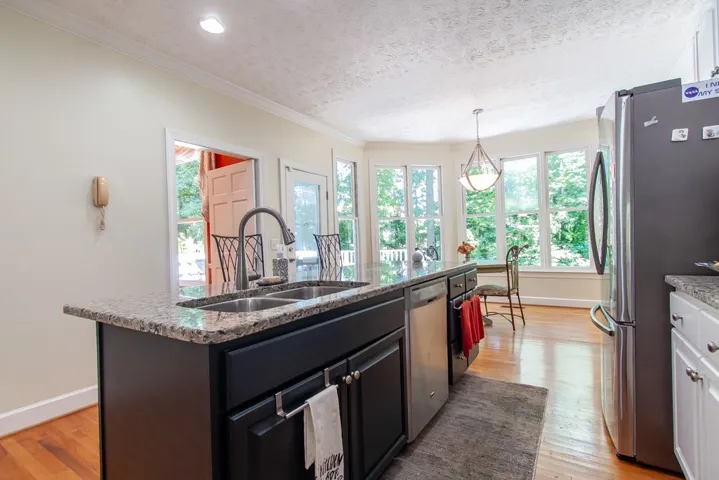 A well-lit kitchen with granite countertops, stainless steel appliances, and a view of surrounding trees.