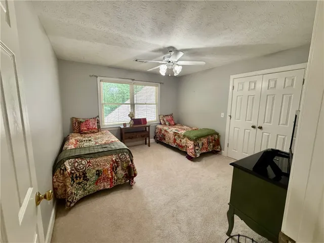 A comforting bedroom with warm neutral tones and a pleasant view of the backyard through a large window.