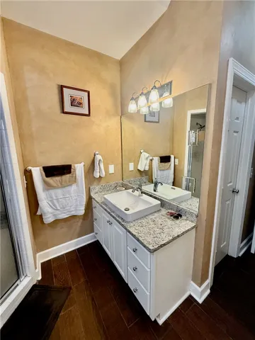 A refined bathroom featuring rich wood flooring and a contemporary vanity with granite counters.