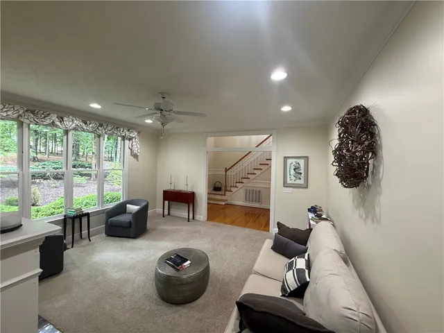 A luminous living area with verdant outdoor views offers a cozy, carpeted retreat.