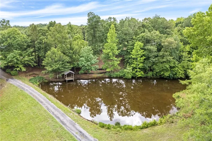 A tranquil pond with a charming gazebo, nestled among mature trees.