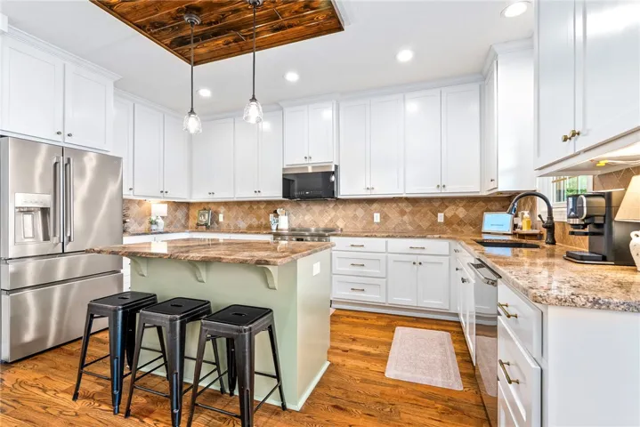 Culinary excellence awaits in this chef's kitchen, featuring an eat-in island, rich hardwood floors, and gleaming stainless appliances.