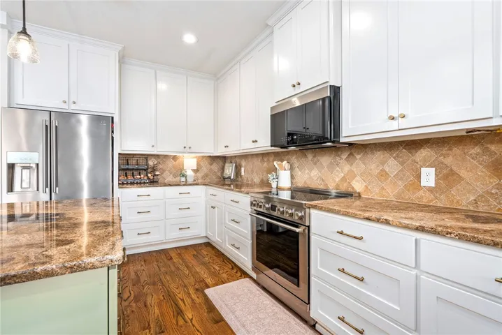 A well-appointed kitchen features rich wood flooring, crisp white cabinetry, and granite countertops.