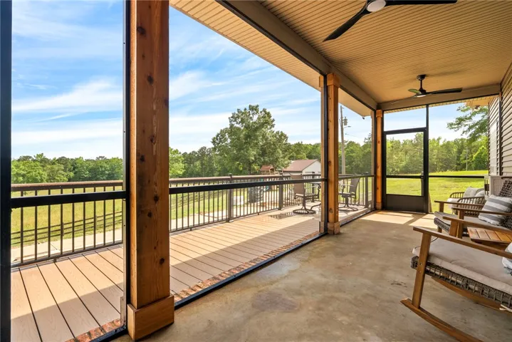 A spacious screened-in porch with wood floors offers serene views of the verdant landscape.