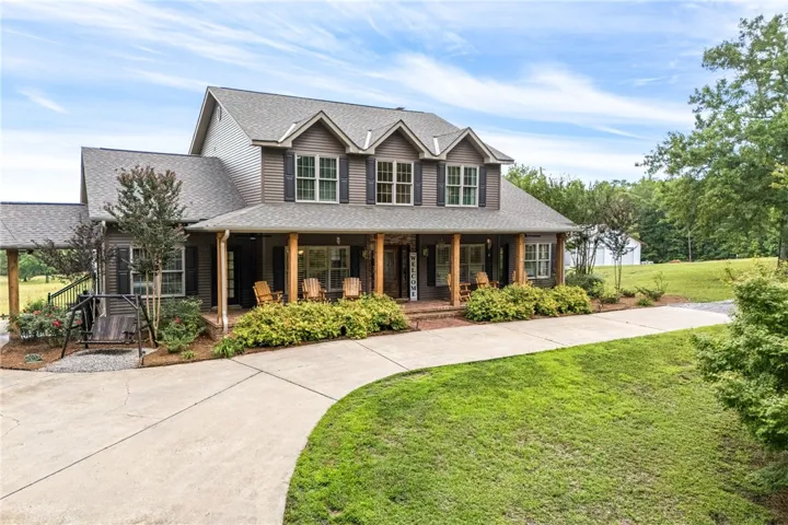 A graceful home with a welcoming front porch, nestled in a verdant landscape.