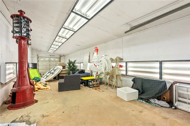 A spacious workshop featuring fluorescent lighting and a large garage door, perfect for projects.